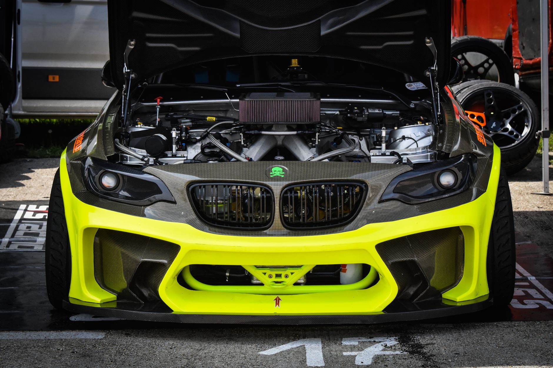 Bright yellow race car with open hood showcasing engine mechanics, highlighting performance parts.