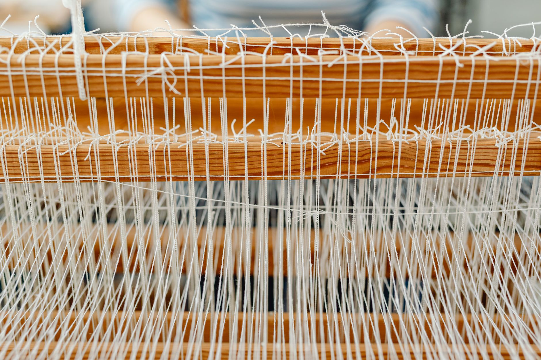 Detailed close-up of a wooden loom with white threads, showcasing traditional weaving.