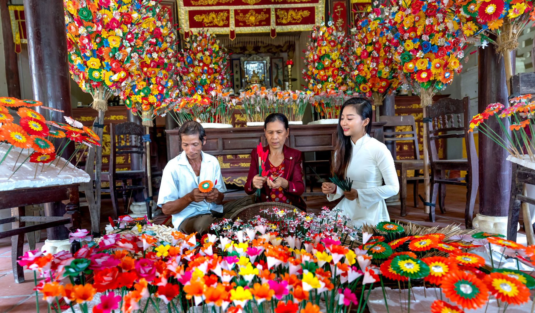 Asian artisans crafting vibrant flowers in a traditional market setting. Cultural and colorful.
