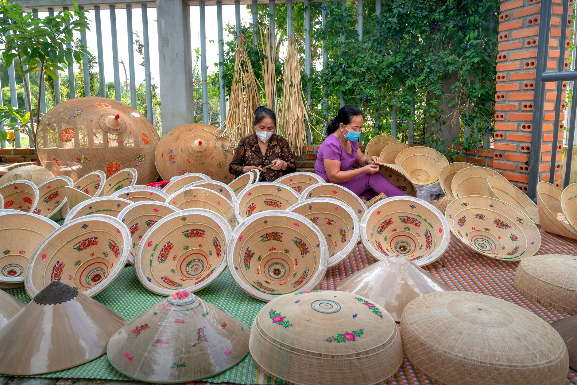 Women crafting traditional conical hats in Vietnam, showcasing cultural artistry.