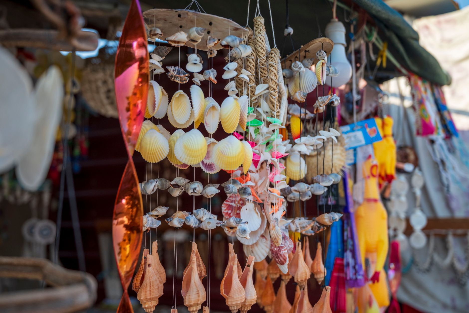 Vibrant display of seashell mobiles at an outdoor market stall, showcasing beach-themed crafts and decor.