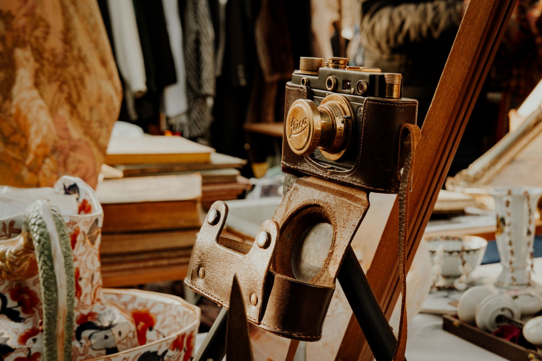A classic vintage camera in a leather case displayed in an antique shop setting.