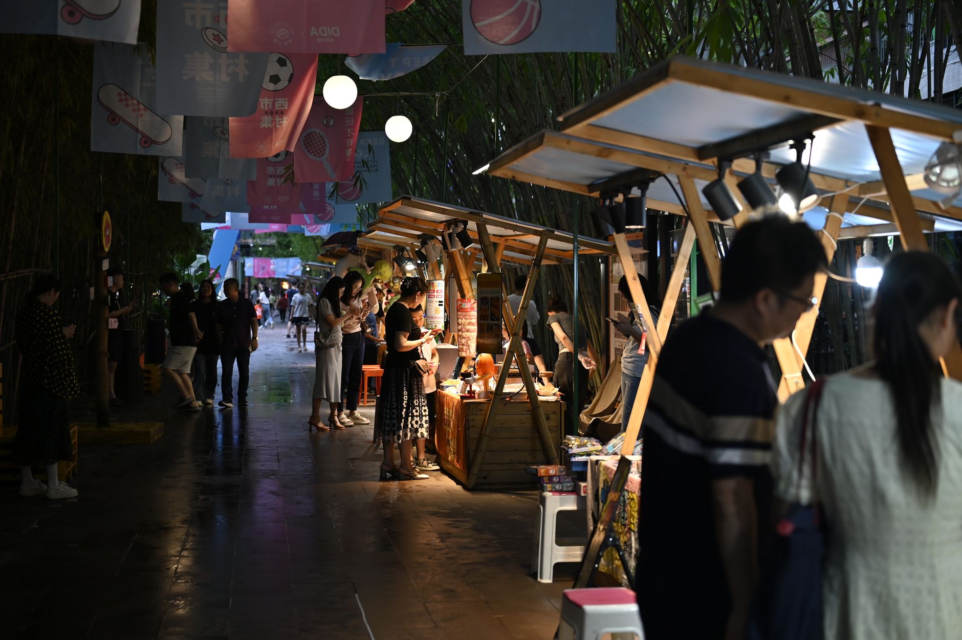 Bustling night market with vibrant stalls, lights, and visitors enjoying the lively ambiance.