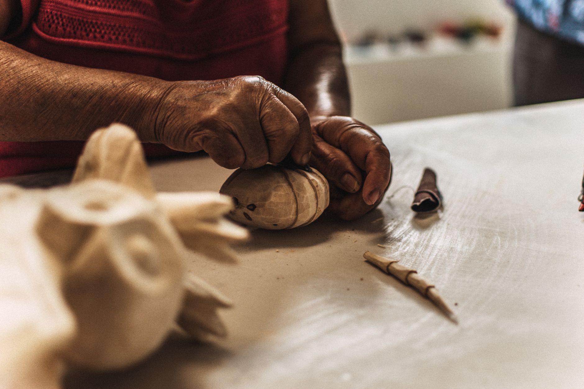 Detailed close-up of hands skillfully carving wood into a sculpture, showcasing traditional craftsmanship.