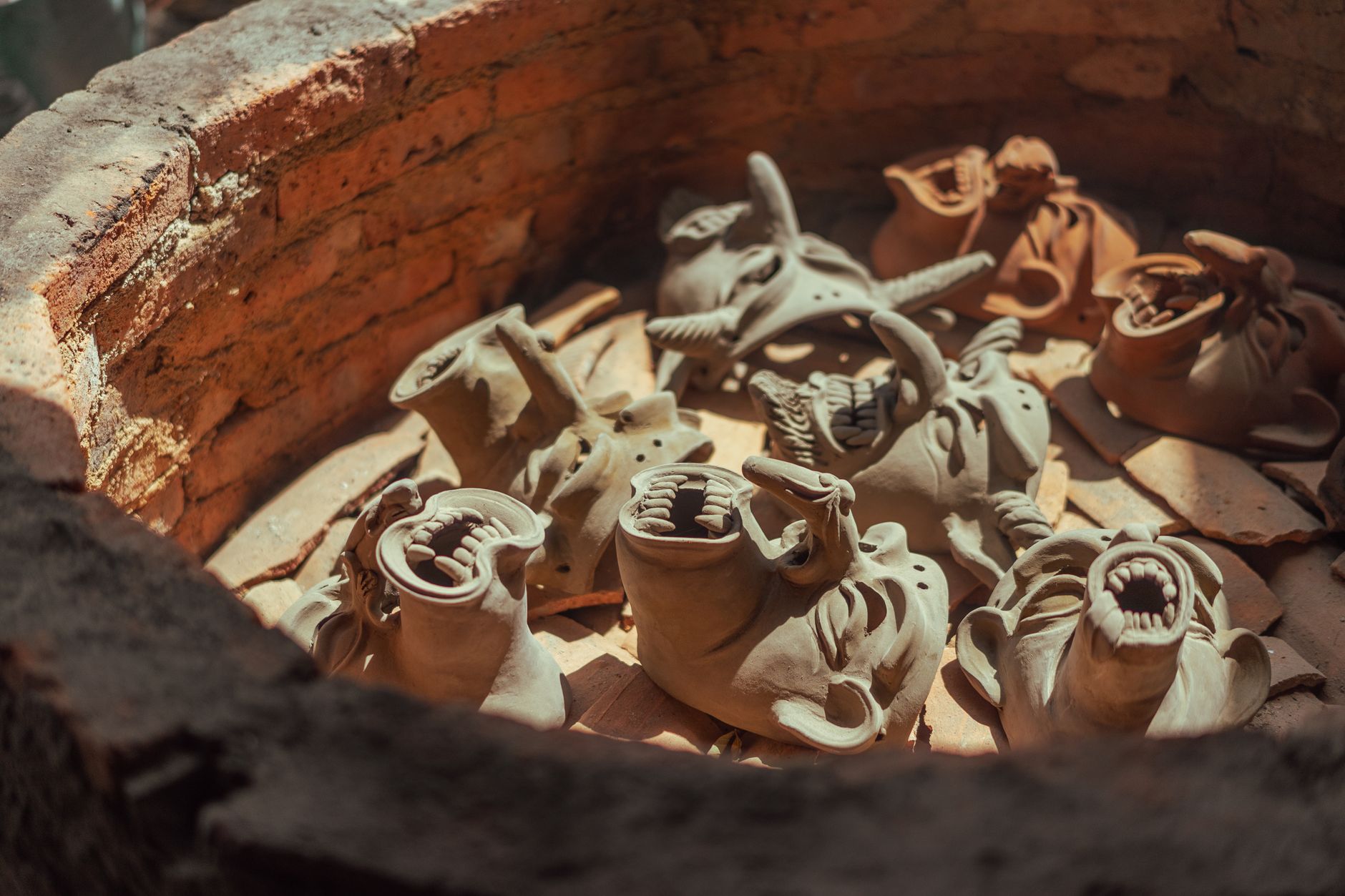 Handcrafted clay masks drying in a kiln with artistic designs.
