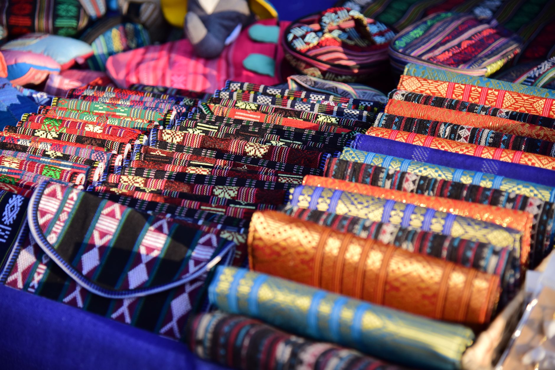 Vibrant handmade textiles on display at an outdoor artisan market showcasing traditional weaving.