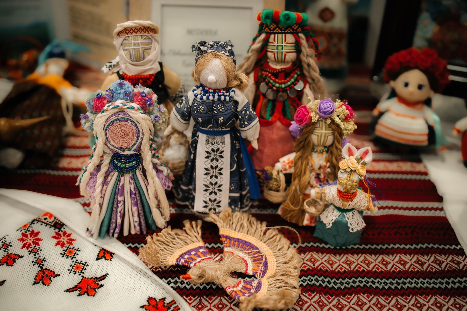 A collection of colorful handmade dolls displayed on embroidered fabric, showcasing cultural artistry.