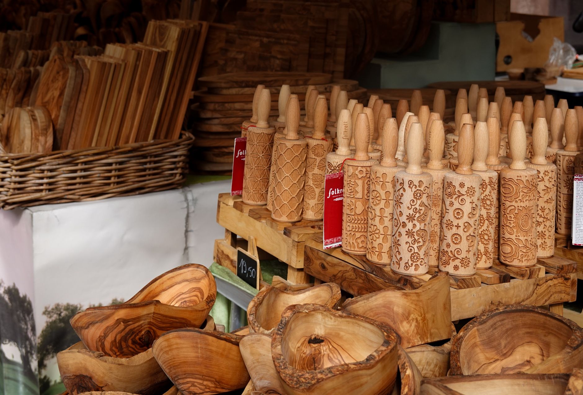 Showcase of intricately carved decorative wooden rolling pins and bowls at a market.