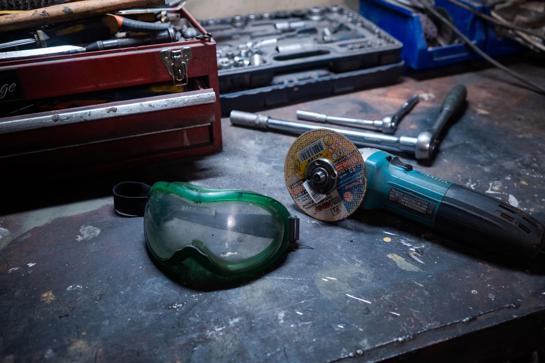 A workshop scene with tools, a grinder, and safety goggles on a workbench.