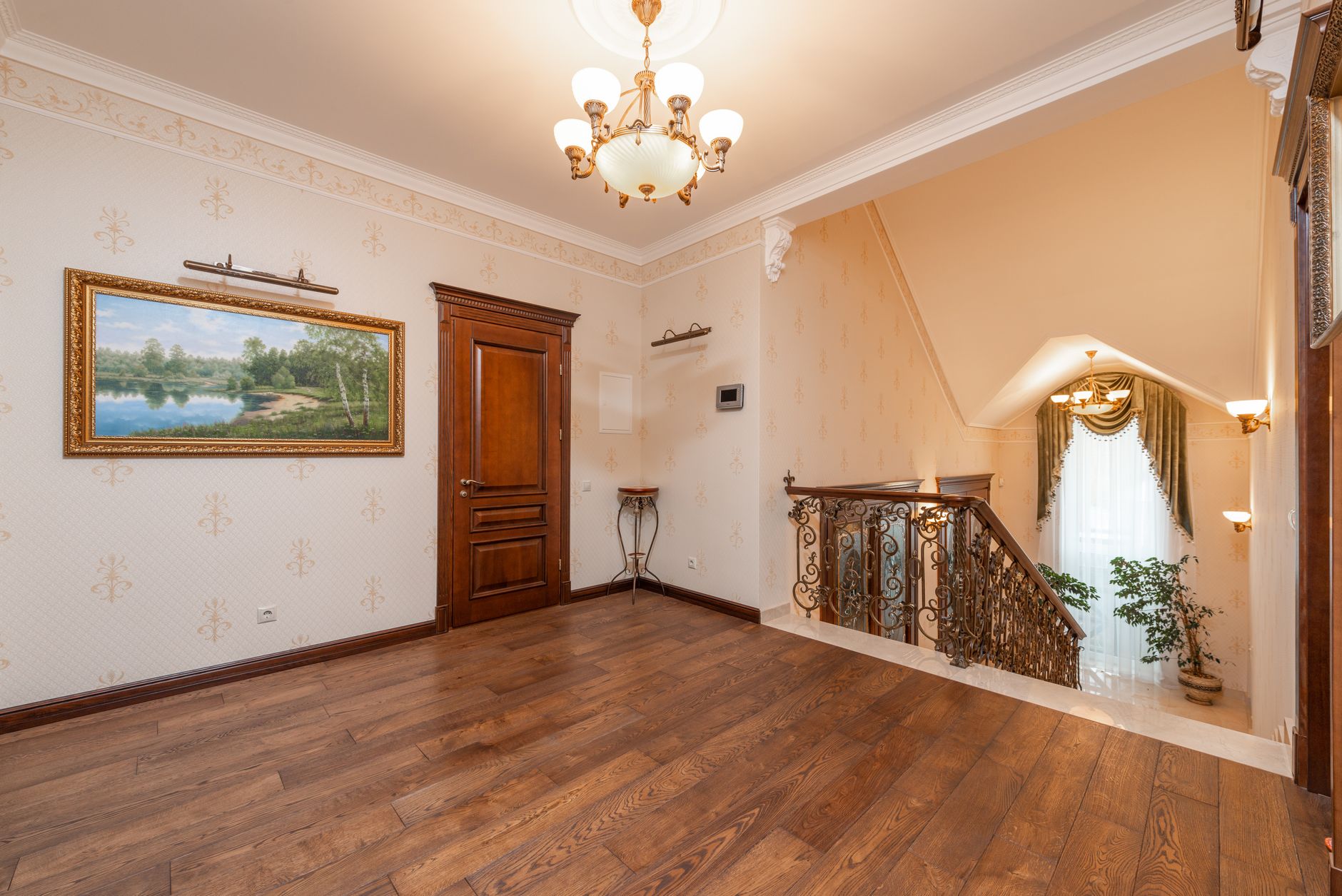 Spacious home interior showcasing elegant staircase, chandelier, and wooden floor.