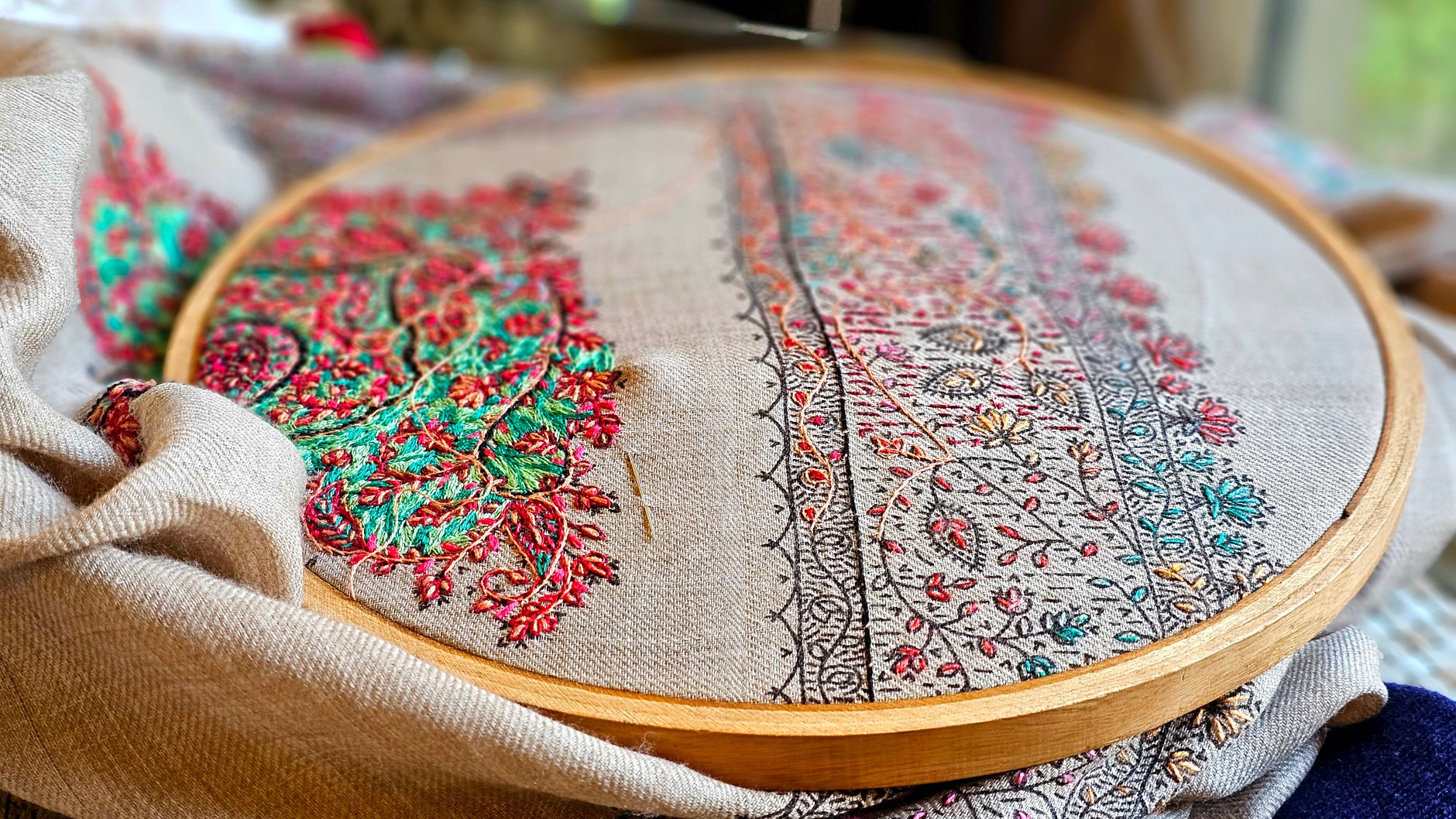 Detailed close-up of colorful embroidery in a hoop, showcasing fine craftsmanship and vibrant thread work.