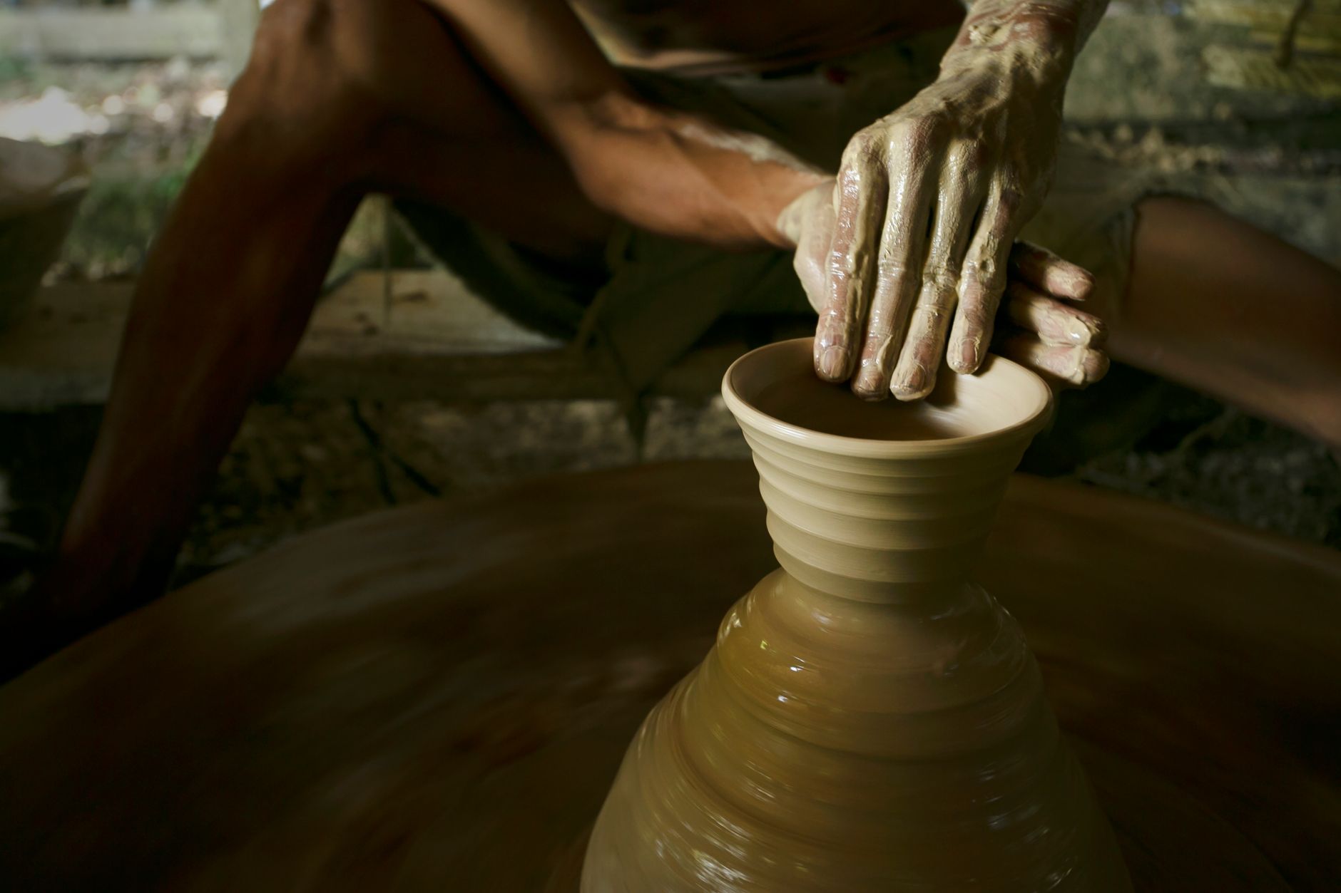 Artisan shaping a clay pot on a potter's wheel, showcasing traditional pottery techniques.