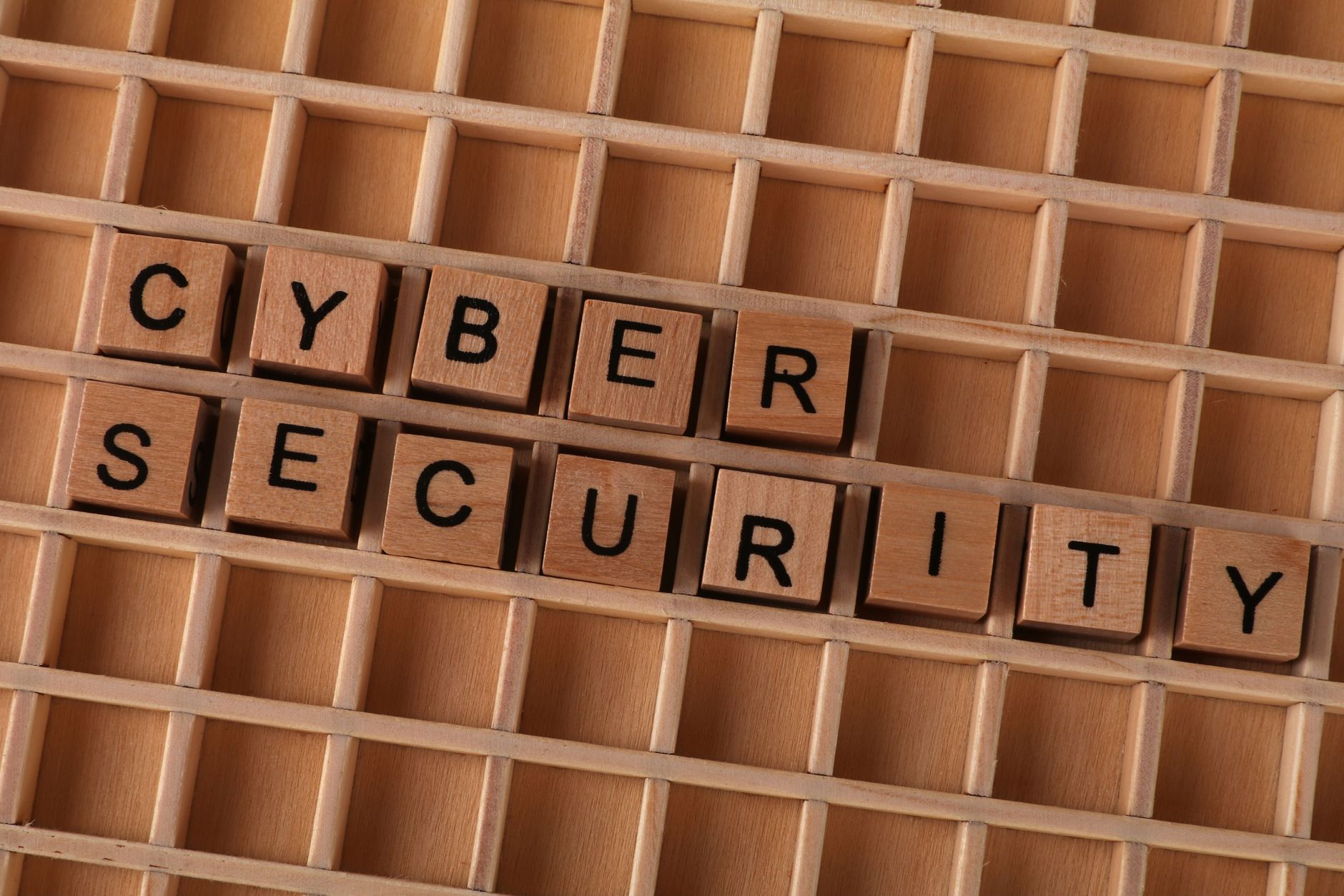 Wooden letter blocks spelling 'CYBER SECURITY' on a wooden grid background for data protection themes.
