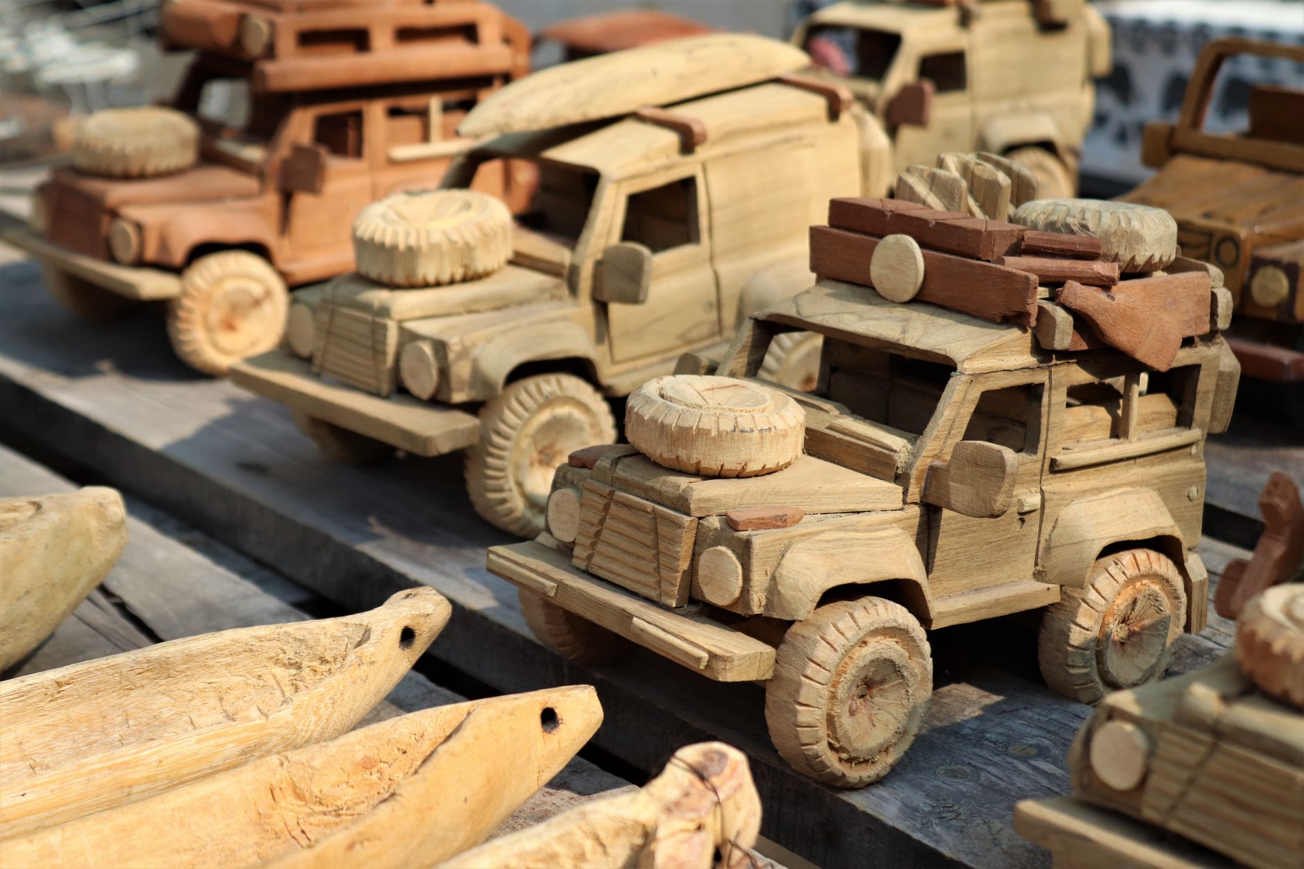 A selection of intricately carved wooden toy trucks displayed at a market. Perfect for souvenirs.