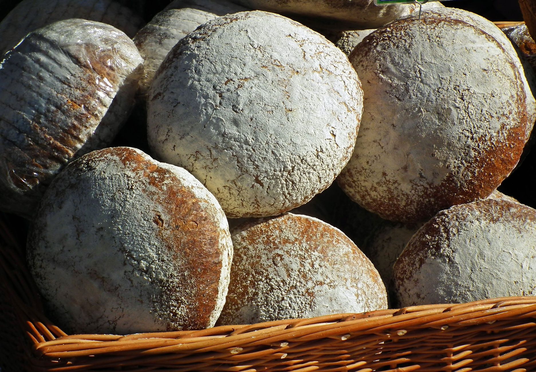 Round artisan bread loaves in a wicker basket, showcasing rustic textures and crusty surfaces.