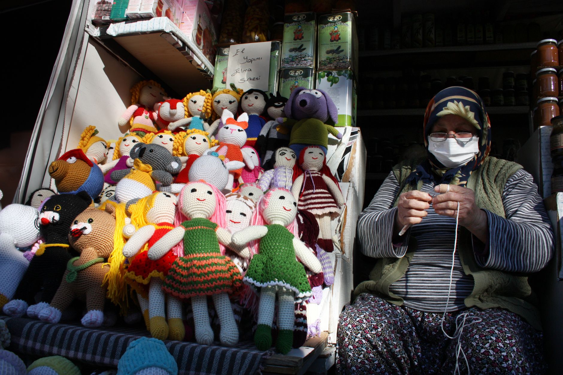 Woman knitting handmade dolls at an outdoor market in Şirince, Turkey.