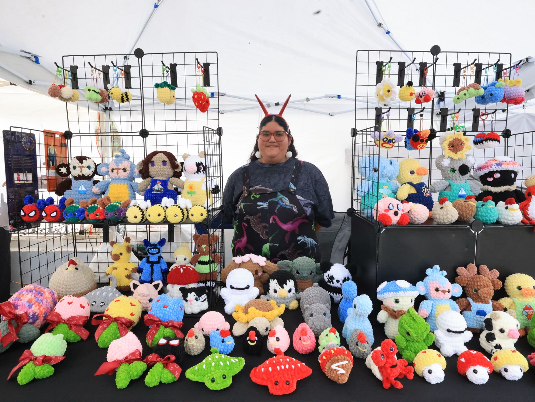 Vibrant crochet toys on display at a busy outdoor craft market.