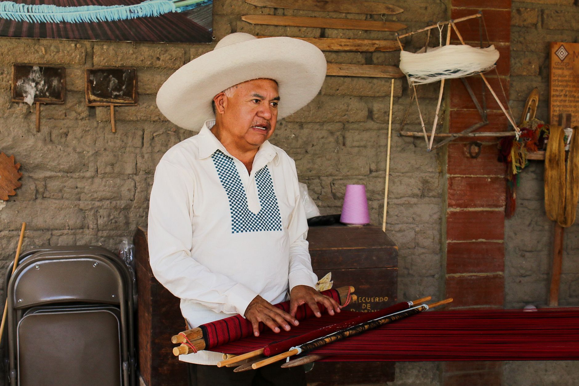 A traditional weaver showcases handmade textile techniques with authentic tools and cultural attire.