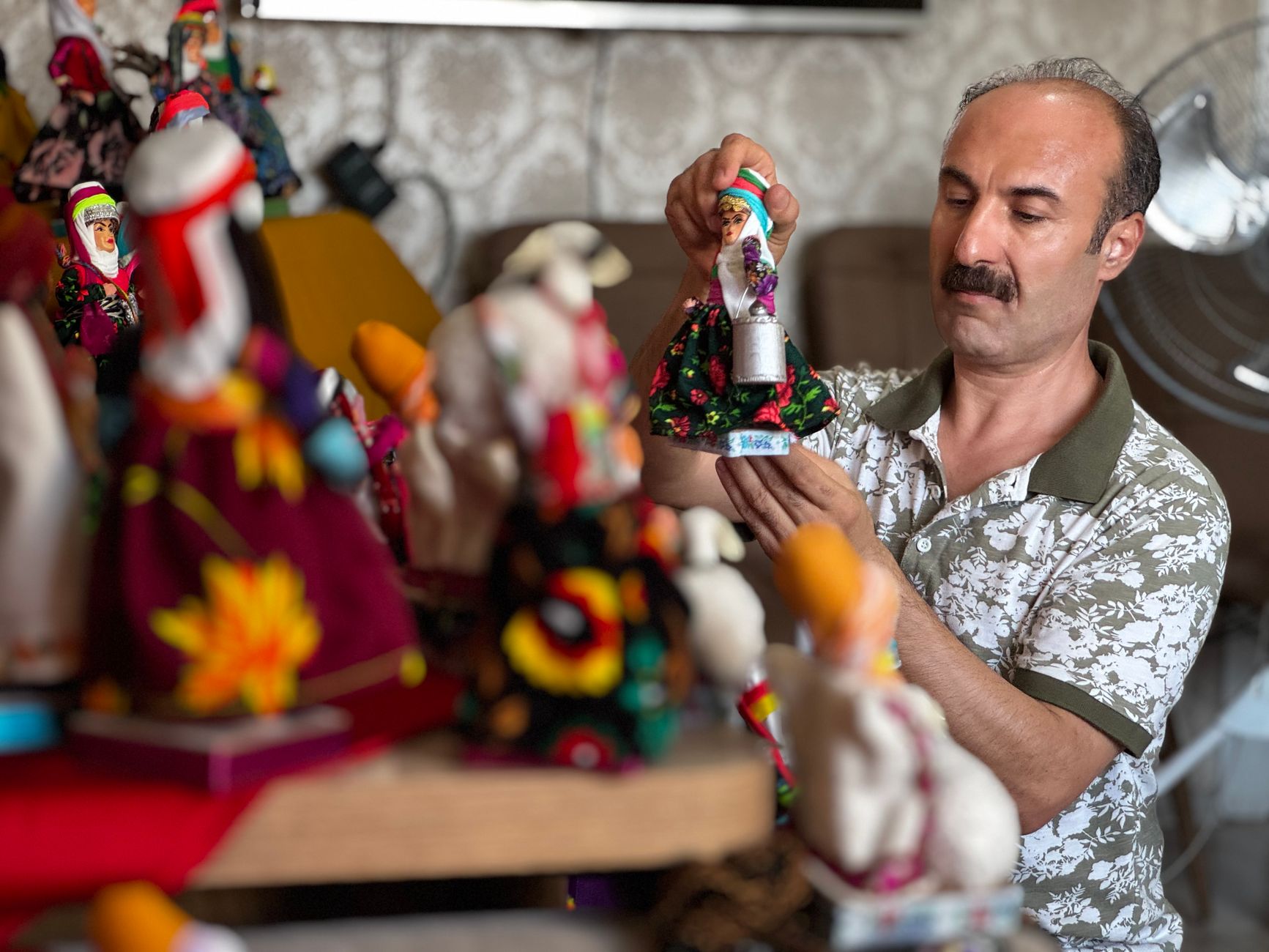 Skilled artisan creating colorful, handmade decorative dolls with intricate details.