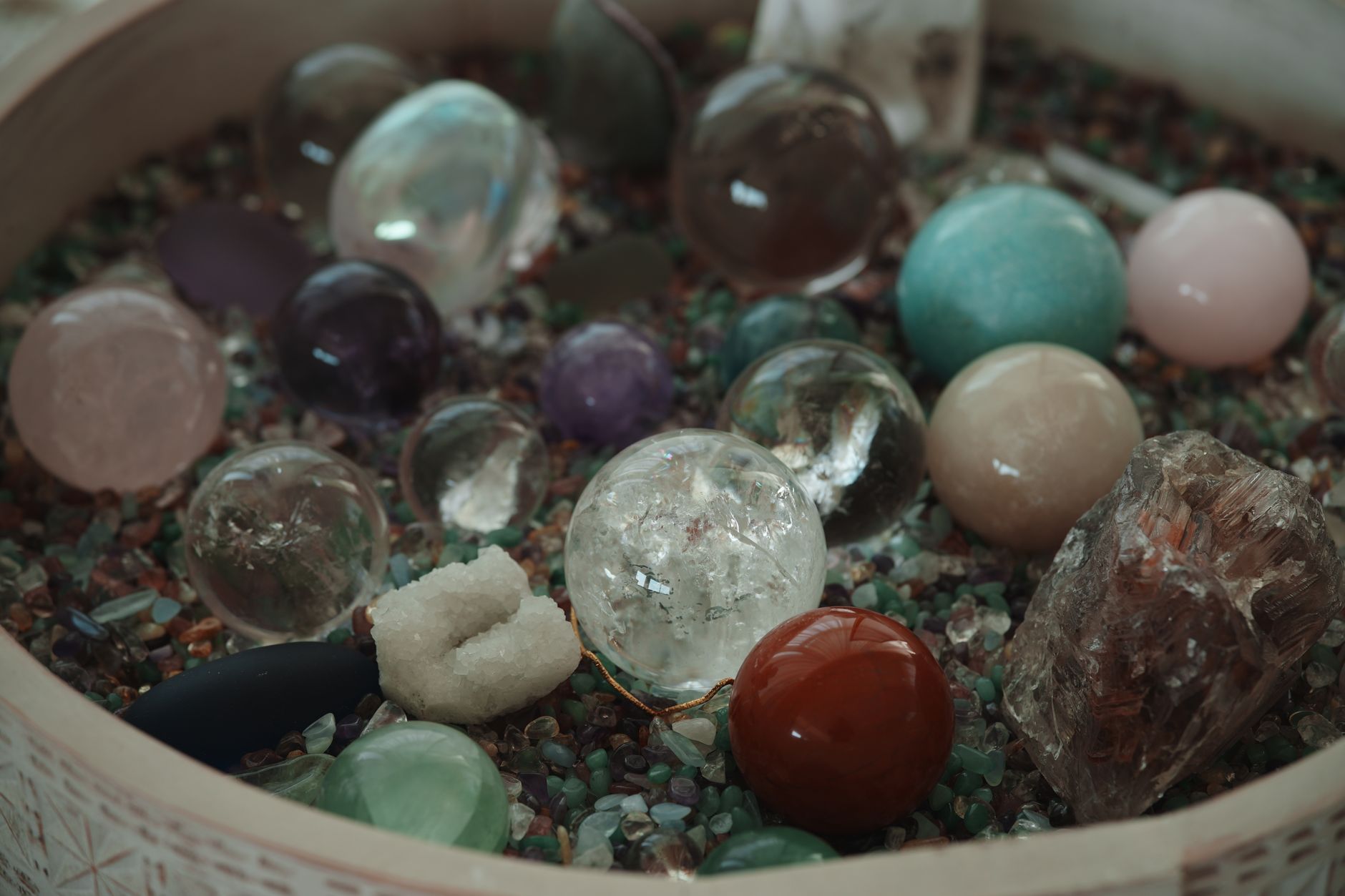 A vibrant assortment of various gemstones and crystals displayed in a decorative bowl.