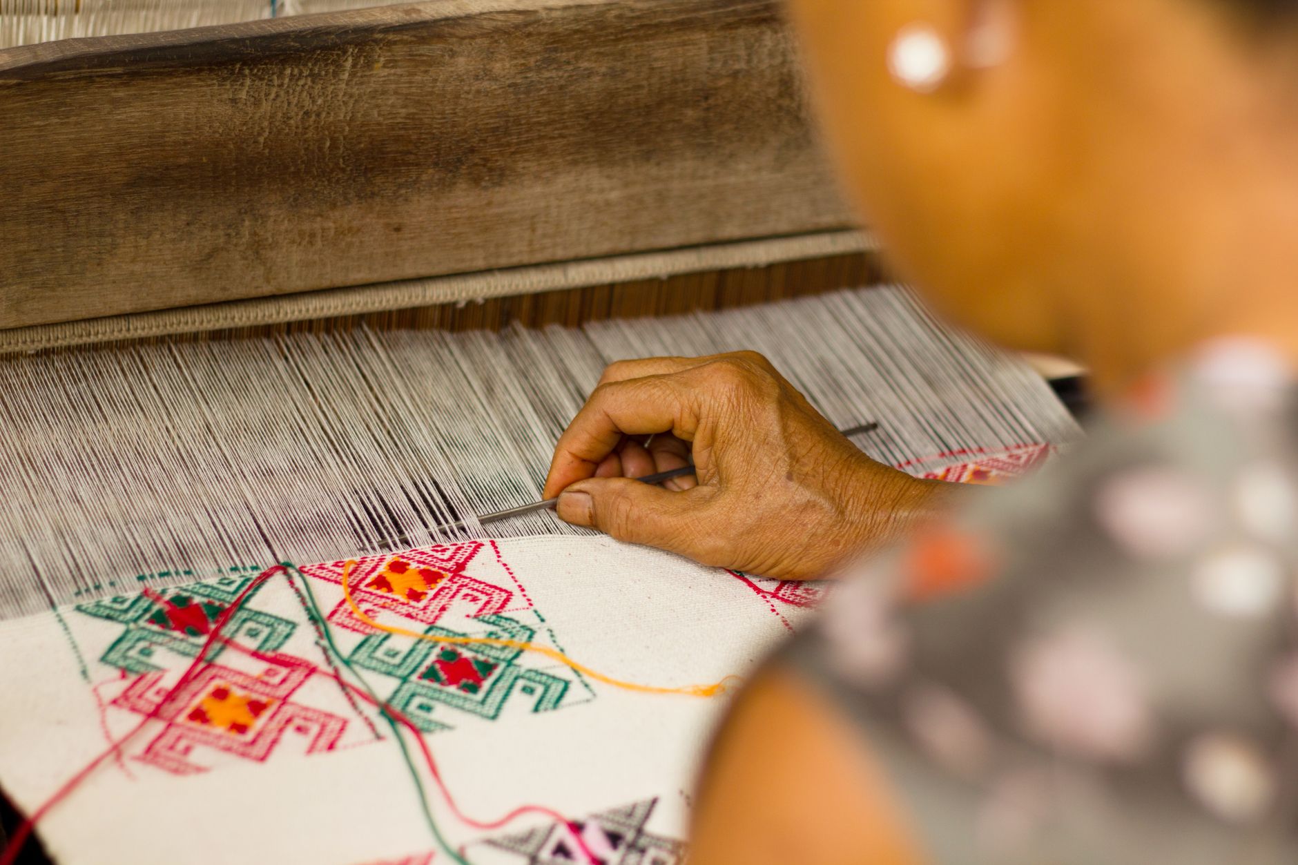 A skilled woman weaver crafting intricate patterns on a textile loom using traditional techniques.