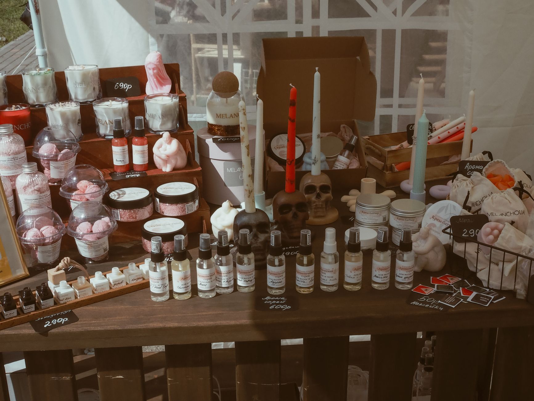 Display of handcrafted candles, skincare items, and decorative pieces at a market stall.