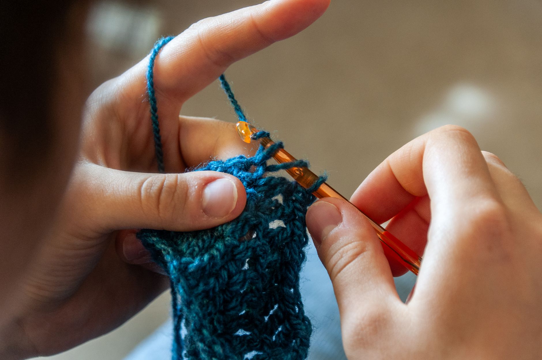 Detailed image of hands crocheting a blue yarn piece with a crochet hook. Ideal for crafting themes.