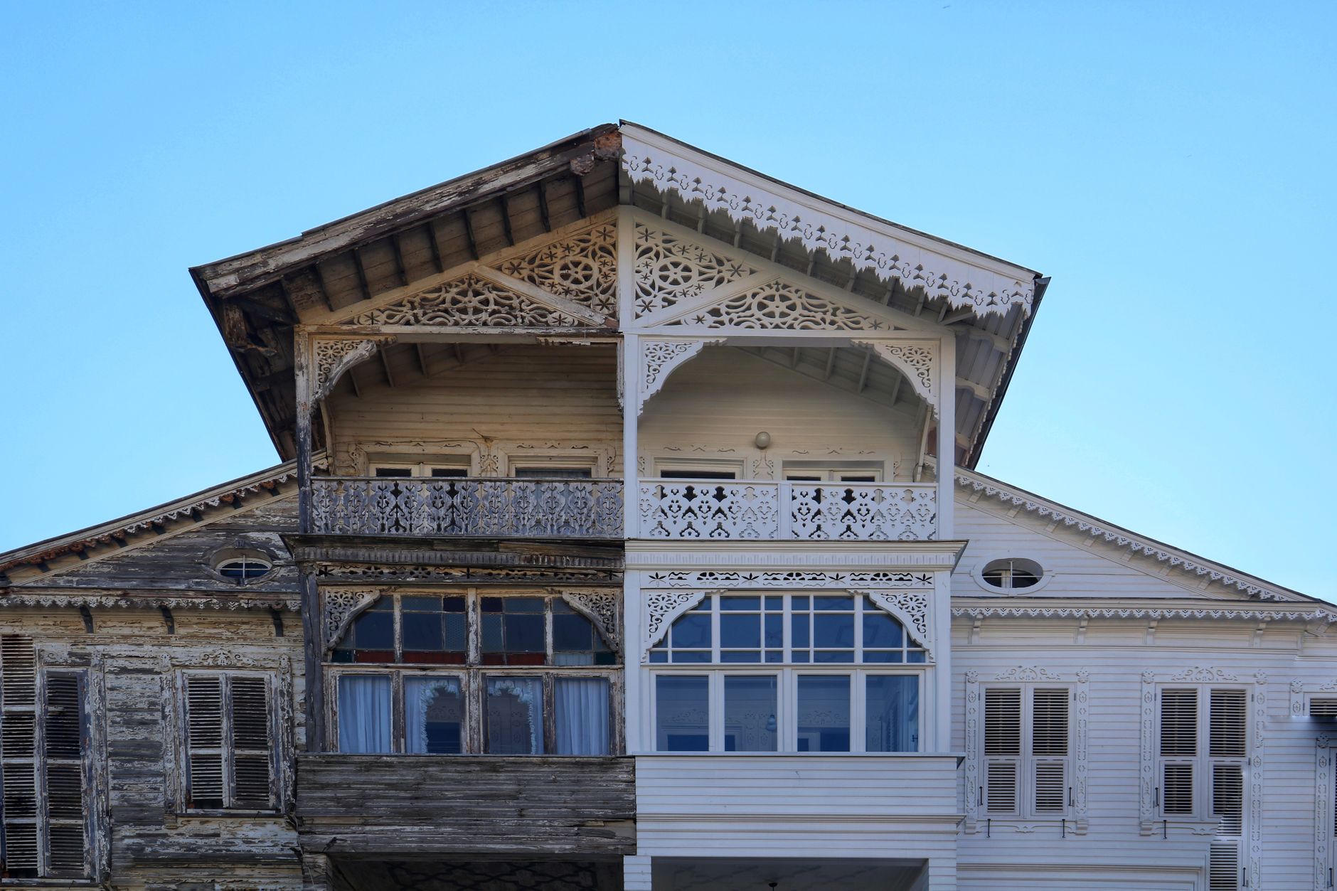 A detailed view of a half-renovated wooden house facade, showing old vs new.
