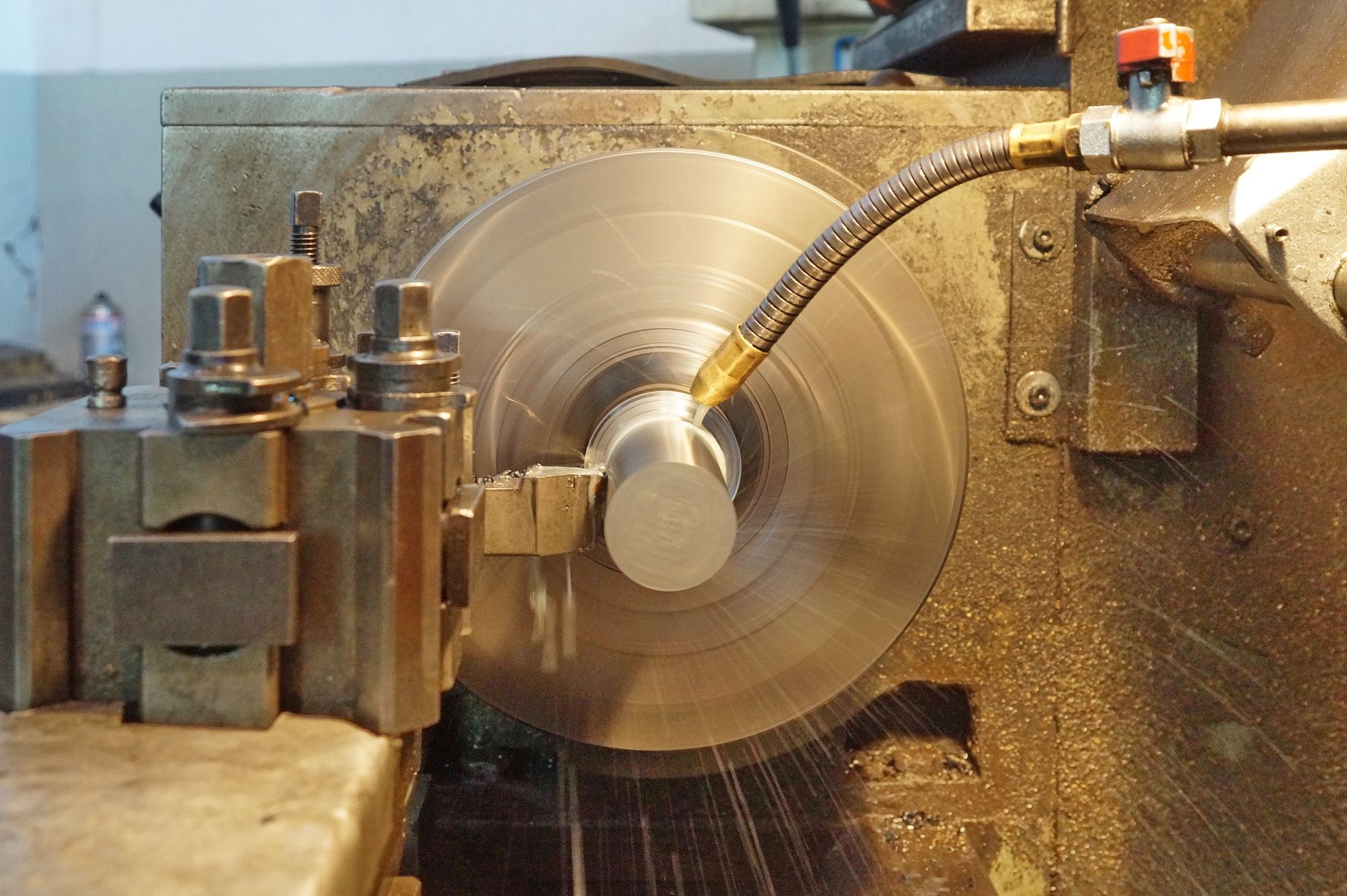 Precision metal lathe in action with metal being machined, indoors workshop.