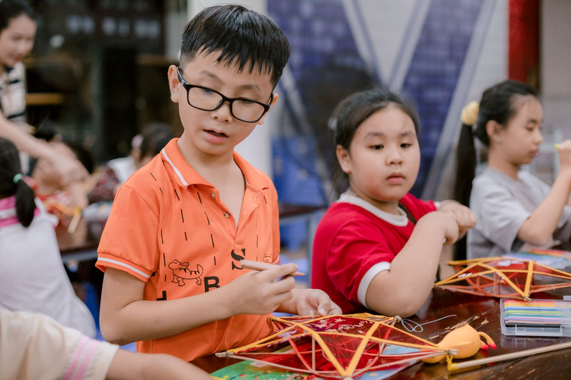 Kids actively participating in a creative arts and crafts session indoors, fostering teamwork and creativity.
