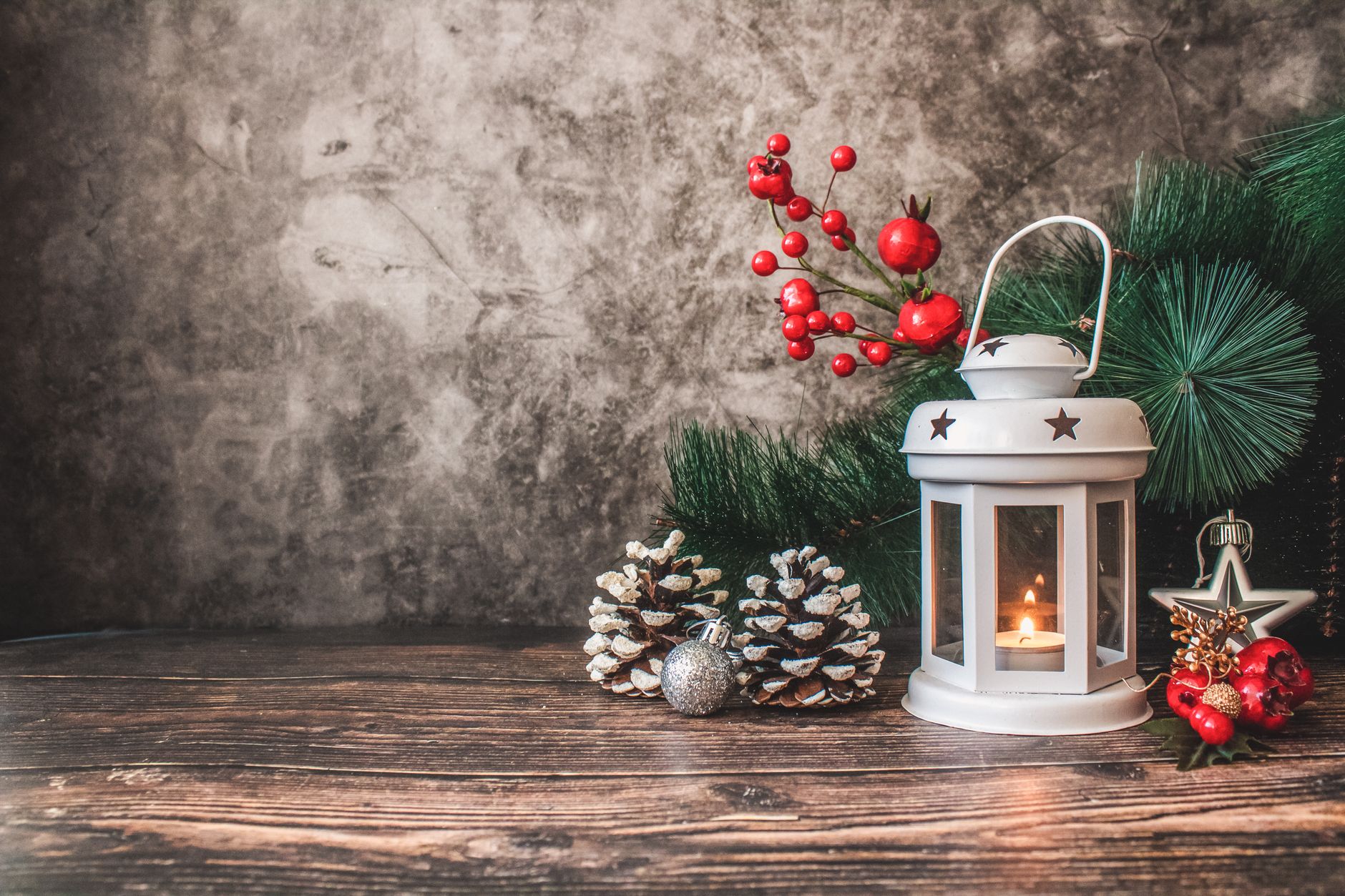 A charming festive arrangement featuring a glowing lantern, pinecones, and Christmas ornaments.